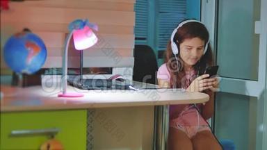 小女孩在智能手机上耳机听音乐。 青少年女孩在社交中翻阅播放列表音乐