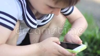 小男孩在智能手机上玩游戏。 春天公园