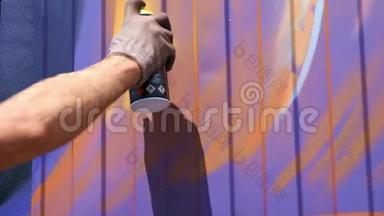 一个带着一罐油漆的年轻人在墙上涂鸦。 一手特写..