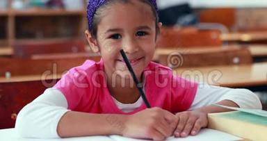教室里可爱的小女孩在书上<strong>涂</strong>着<strong>颜色</strong>，对着镜头微笑