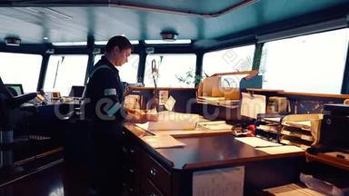 在桥上航行监视期间的海洋导航员。 他做图表修正