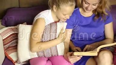年轻的妈妈在<strong>睡前</strong>在沙发上的客厅里大声地给女儿读一本书
