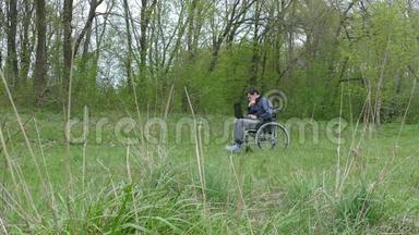 残疾人认为轮椅上的笔记本电脑在自然绿色背景下工作已经很累了