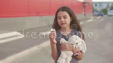 <strong>吃</strong>冰淇淋的小女孩走在街上，有一个柔软的玩具动作慢动作<strong>视频</strong>。 女孩和冰淇淋<strong>吃</strong>