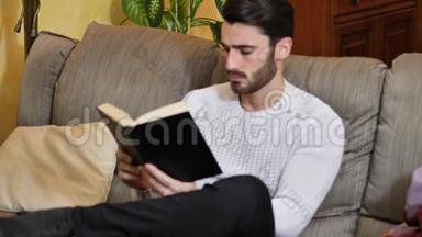 英俊的年轻人在家看书，坐在沙发上