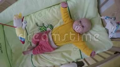 有兴趣的宝宝看着旋转木马玩具在她的床上旋转。 4K