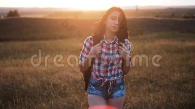 年轻姑娘背着背包走着，在峰后欣赏日落。 背景视图上的游客模型慢