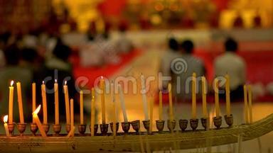 佛日在佛寺。 人们点燃蜡烛、鲜花和香棒。 沃特纳哈拉姆，普吉，泰国。 慢慢