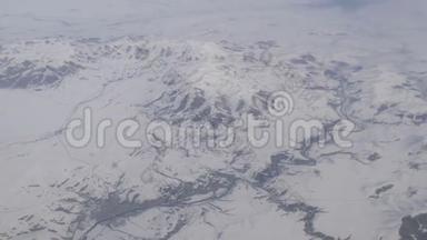 令人惊叹的山脉美景，微微覆盖着雪，从云中掠过，从飞机窗口眺望