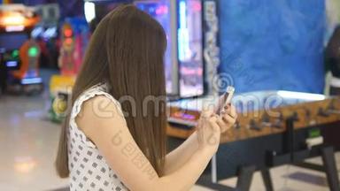 年轻女子在购物中心<strong>玩</strong>室内游戏，使用智能<strong>手机</strong>。 女孩<strong>玩</strong>流行的智能<strong>手机</strong>游戏-捕捉