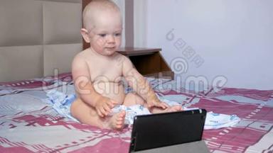 可爱的孩子坐在床上盯着<strong>平板</strong>电脑上的<strong>卡通</strong>。一岁的小婴儿，没有衣服