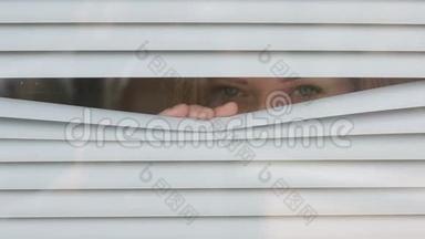 女人透过百叶窗看着窗外的街道，监视着。 嫌疑犯