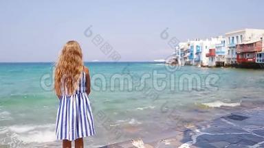 可爱的小女孩在小威尼斯最受欢迎的旅游区米科诺斯岛，希腊。 美丽的孩子微笑