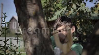 有趣的男孩躲在树后面，用弹弓瞄准户外
