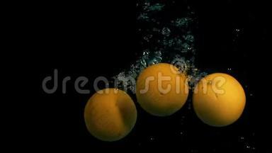 黑色背景下缓慢运动的橘子落入水中