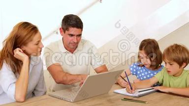 家长使用笔记本电脑，孩子在餐桌上涂颜色