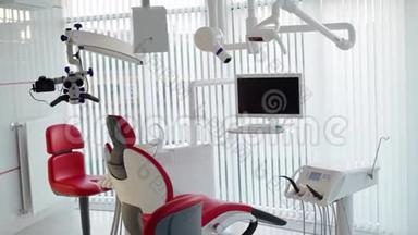 白色牙医办公室。 奢华的极简牙科诊所内部配有红色椅子和工具、玻璃墙上的牙科灯