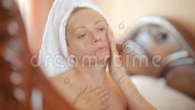 女人<strong>敷面膜</strong>保湿护肤霜在脸上照镜子。
