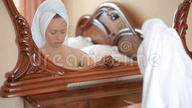 女人敷面膜保湿护肤霜在脸上照镜子。