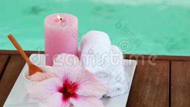 泳池旁的毛巾、蜡烛和粉红色的花