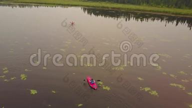一对夫妇在皮划艇上划水，享受着平静、朦胧的湖泊。