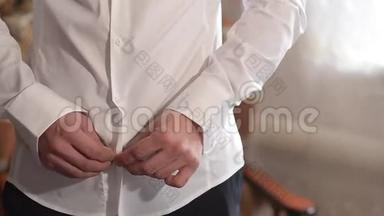 男人穿上白色衬衫，男人把纽扣系在白色衬衫上。