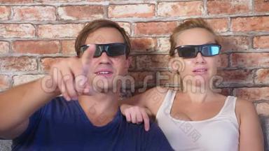 关<strong>上门</strong>。 一对年轻夫妇戴着3D眼镜，坐在客厅的沙发上，带着许多情绪，看电影。 4k