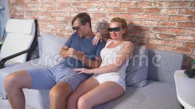 关上门。 一对年轻夫妇戴着3D眼镜，坐在客厅的沙发上，带着许多情绪，看电影。 4k