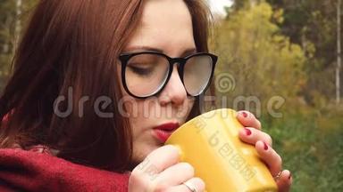 年轻女子从杯子里喝热茶以保暖