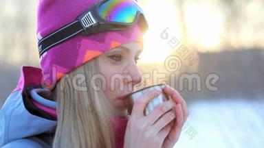 女人手里拿着热水瓶里的杯子，在雪白的树枝上喝茶