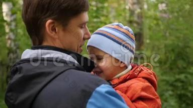 一个年轻的父亲把他的孩子抱在怀里。 温柔和怀抱的挚爱父亲.. 户外活动