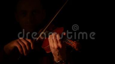 小提琴手在黑色背景下拉小提琴。 关门