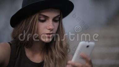 戴着黑帽子的漂亮女孩正在智能<strong>手机</strong>上<strong>输入</strong>一条信息