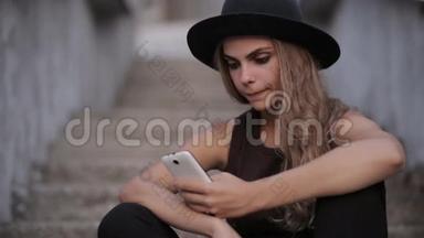 戴着黑帽子的漂亮女孩正在智能手机上输入一条信息