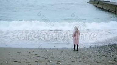 暴风雨中穿着粉红色外套，带着透明雨伞的女孩在海边。