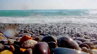 卵石海滩，小卵石和海浪。 船在海上。 海的表面在一个野生鹅卵石海滩上。 波浪是
