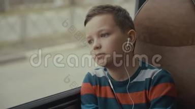 一个小<strong>男孩</strong>乘公共汽车穿过城市的特写镜头。 他<strong>听音乐</strong>。