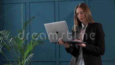 自信的女商人在她现代蓝色的现代办公室里使用笔记本电脑。时尚美女做