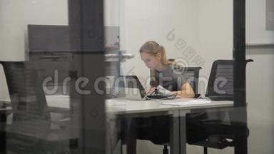 女雇员正在现代办公室用笔记本电脑办公。