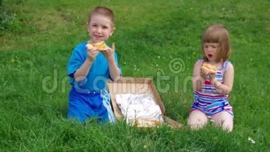 在草地上野餐.. 男孩和小女孩在草地上吃披萨。