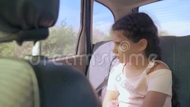 伤心的女孩无聊地坐在车里后座<strong>旅行</strong>。 小女孩在车里无聊。 概念概念<strong>长途旅行</strong>
