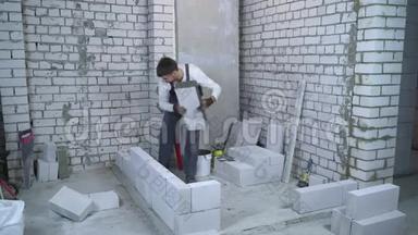 男建筑工人铺设加气混凝土砌块，并用气泡水平检查