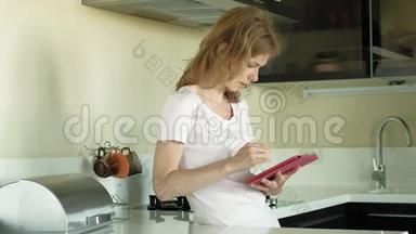 厨房里的女人用平板电脑，刚醒过来。 早餐。 清晨