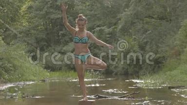 美丽的女孩在森林河的中央戏水
