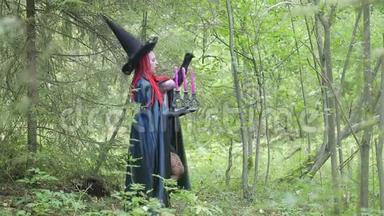 年轻的女巫，红色的头发，黑色的帽子和黑色的斗篷，在<strong>森林</strong>里的蜡烛。