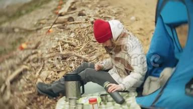河岸上的旅游<strong>帐</strong>篷。 两个<strong>女孩</strong>坐在<strong>帐</strong>篷附近吃喝看着河。