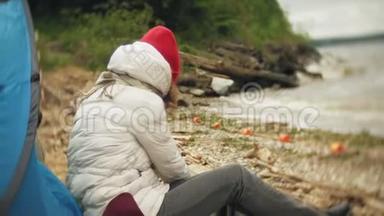 河岸上的旅游<strong>帐篷</strong>。 两个女孩坐在<strong>帐篷</strong>附近吃喝看着河。
