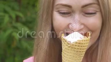 女人舔冰淇淋。 女孩在舔一个美味的奶油冰淇淋。 有草莓味的冰淇淋甜筒