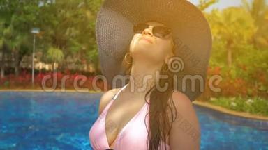游泳池边戴蓝帽子的漂亮女孩。 夏日的阳光。 慢动作
