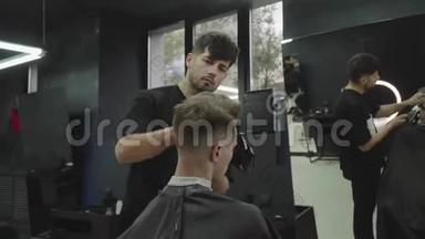男式理发用电动剃须刀.. 理发师在理发店为顾客理发. 男子